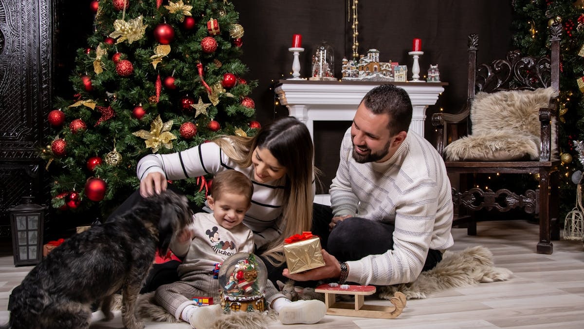 A joyful moment with family by the Christmas tree, gifting and playing with a dog.